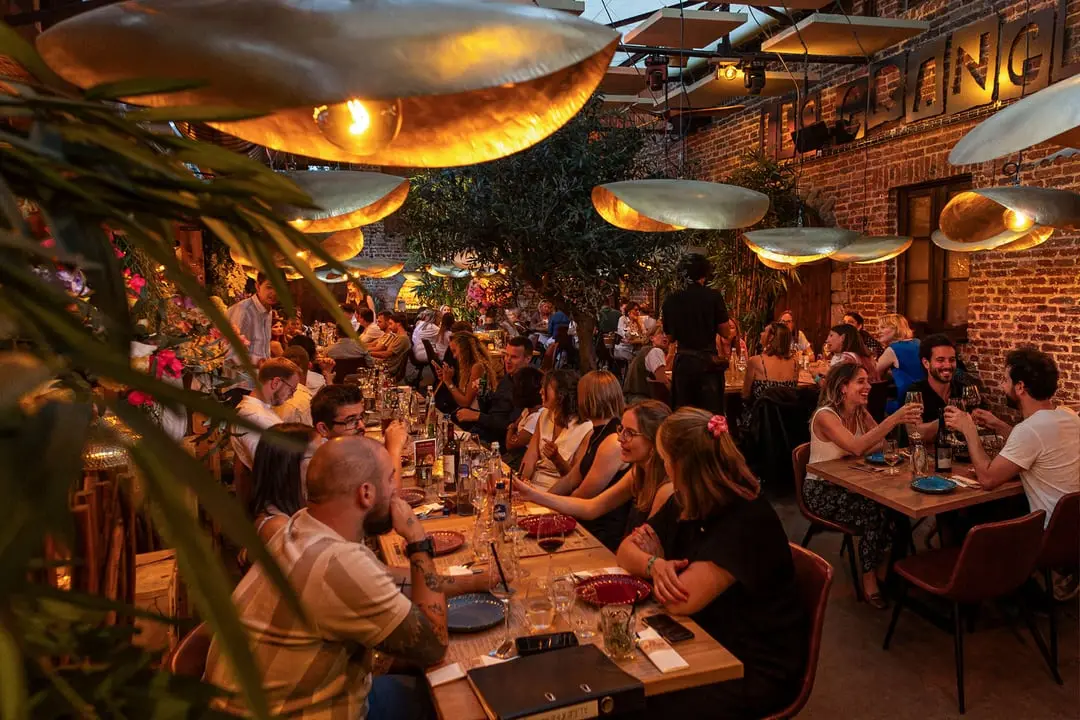 Les Granges — grande tablée sous les lampes en laiton, le long du mur de briques