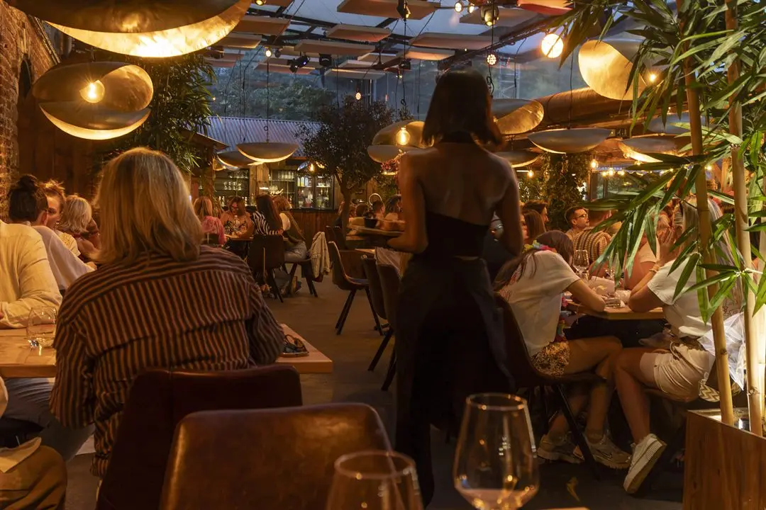 Les Granges — la terrasse couverte, tables dressées sous les lampes en laiton